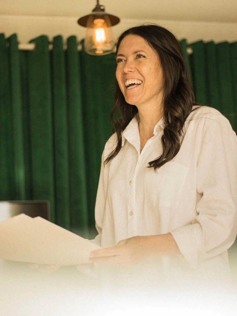 A director seated at a kitchen table with a laptop and coffee at dawn.