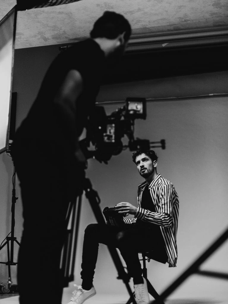 A veteran filmmaker stands in a cramped editing suite with film reels behind him.